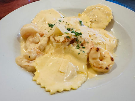 A plate of shrimp ravioli covered in cream sauce with cheese