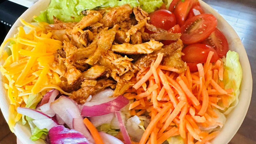 A bowl filled with colorful carrots, tomatoes, cheese, chicken, guacamole and rice from Haystax in Charleston, WV