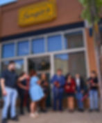 A crowd stands in front of a ribbon cutting for a new restaurant