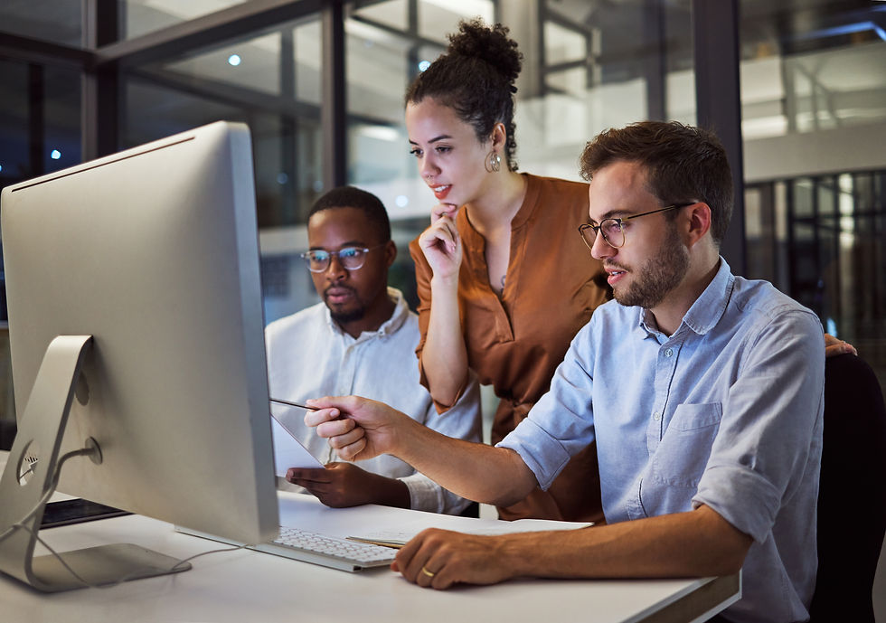 Two men and one woman working on a desktop computer