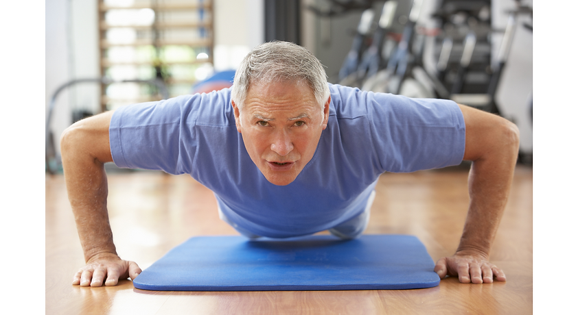 Older man performing a push-up on a mat to build upper body strength and improve fitness in a gym environment