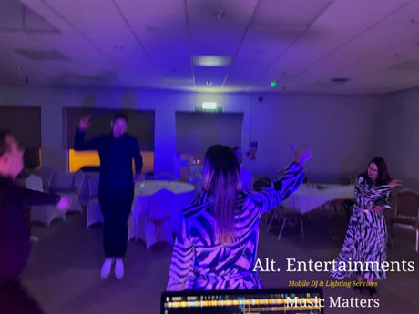 Wedding guests dancing energetically on the dancefloor at Wolverhampton Lawn Tennis & Squash Club in Tettenhall, illuminated by ambient lighting and festive decor. Photo by Alt. Entertainments Wedding DJ/Mobile DJ, Disco & Events Company.