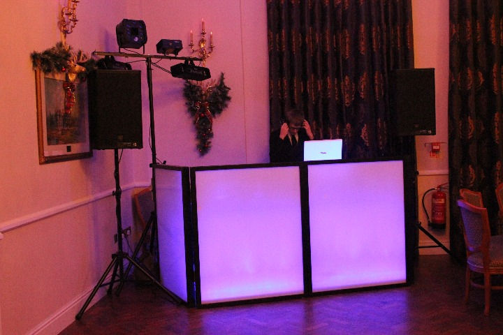 A festive DJ setup adorned with dazzling lights and cutting-edge equipment, illuminating the Christmas Party hosted by Alt. Entertainments (Mobile DJ, Disco & Events) at Brocton Hall Golf Club in Staffordshire. The vibrant ambiance sets the stage for a night of joyful festivities and merry moments.