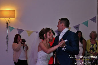Bride and groom sharing their first dance at a wedding disco, illuminated by warm lights at Mythe Barn in Atherstone, Leicestershire. Photo taken by Alt. Entertainments, a wedding DJ, mobile DJ, disco, and events company, capturing the romance and joy of this special moment.