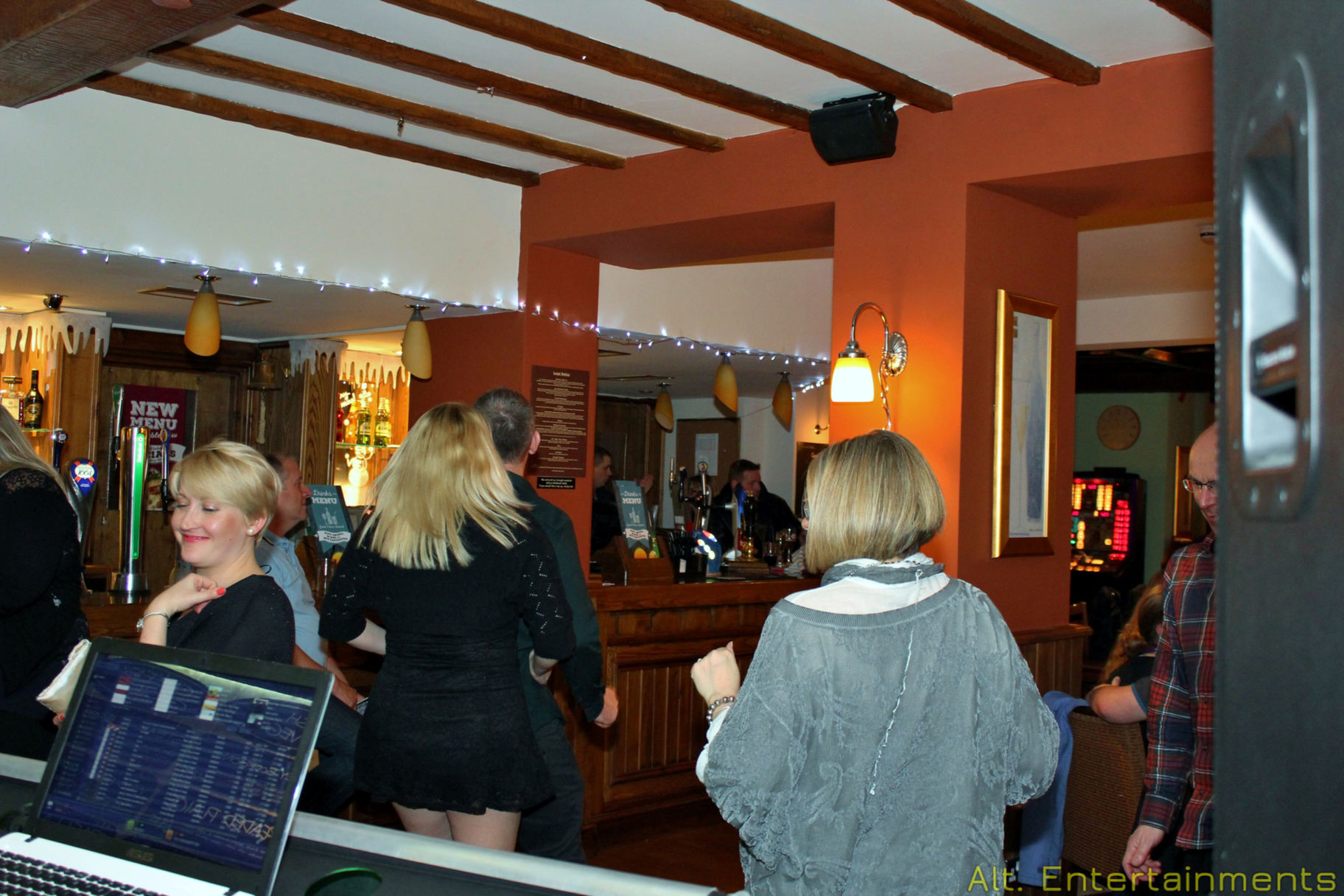 A lively crowd dances amidst vibrant disco lights at The Crown's New Year's Eve celebration in Wychbold, Droitwich, Worcestershire. Captured by Alt. Entertainments, a mobile DJ, disco & events company, the photo captures the festive atmosphere, with attendees immersed in the joyous festivities of the night.