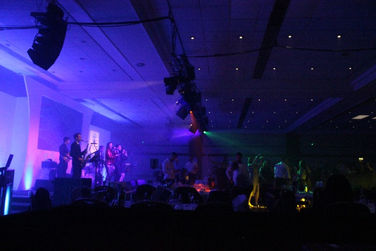 A lively band delivers an electrifying performance at a corporate event held at the Hilton Birmingham Metropole Hotel in Solihull. The photo, captured by Alt. Entertainments, showcases the vibrant atmosphere of the occasion.