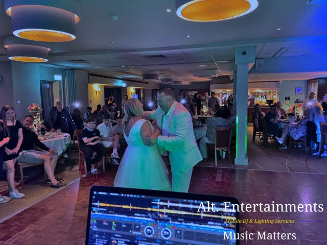 Bride and groom share their first dance under fairy lights in the elegant function room of Copt Heath Golf Club, Knowle, surrounded by applauding guests; music and lighting by Alt. Entertainments Wedding DJ/Mobile DJ, Disco & Events Company.