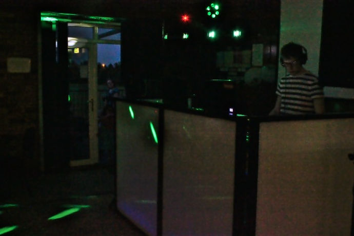 A dynamic mobile DJ setup at Vipers RFC in Whetstone, Leicestershire, featuring a professional DJ at the console surrounded by high-quality audio equipment and dazzling lights. The photo, taken by Alt. Entertainments, captures the vibrant atmosphere and expert setup that define their renowned mobile DJ, disco, and events services.