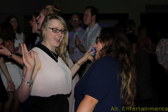 A lively birthday party scene at the Beacon Centre For The Blind in Dudley, showing guests dancing energetically on a vibrant dance floor. The photo, taken by Alt. Entertainments, features dynamic lighting and a professional DJ setup, capturing the festive atmosphere and enjoyment of the event.
