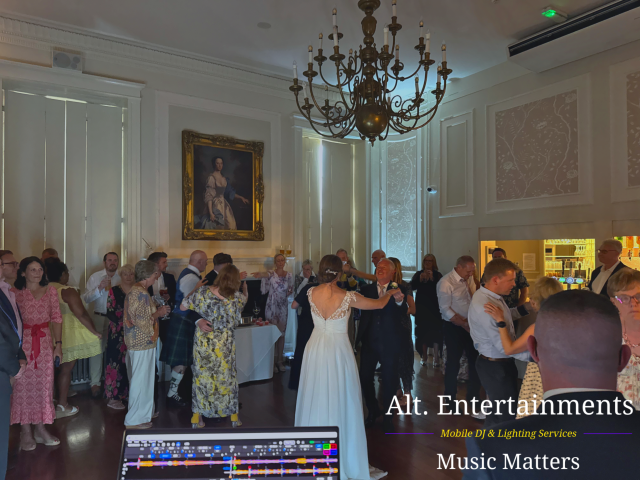 Bride and groom sharing their first dance at a wedding reception in Rowton Castle, Halfway House, Shropshire, surrounded by guests in an elegant castle setting with professional DJ entertainment by Alt. Entertainments.