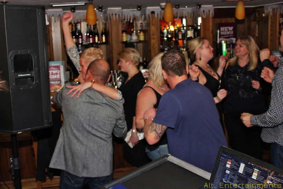 A vibrant crowd dances joyfully at The Crown in Wychbold, Droitwich, Worcestershire, on New Year's Eve. Captured by Alt. Entertainments, a mobile DJ, disco & events company, the photo showcases attendees grooving under sparkling disco lights, embodying the spirit of celebration and anticipation for the new year.