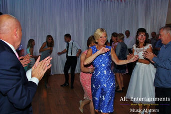 Guests dancing energetically at a wedding disco in Crosby, Liverpool, captured by Alt. Entertainments. The lively dance floor is adorned with colorful lights and decorations, creating a festive atmosphere. Alt. Entertainments, specializing in Wedding DJ, Mobile DJ, and event services, is noted for their ability to enhance celebrations with vibrant and memorable experiences.