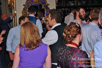 Guests dance energetically at a wedding disco at Merewood Country House in the Lake District, Cumbria. The lively scene, captured by Alt. Entertainments, a wedding DJ and mobile disco company, shows the crowd enjoying the music and celebrating. The elegant venue enhances the festive atmosphere of the evening.