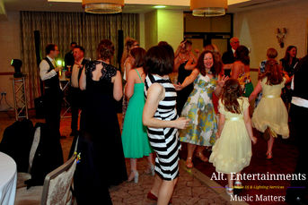 A lively scene of wedding guests dancing joyfully at a wedding disco held at Lodore Falls Hotel & Spa in the Lake District, Cumbria. The image captures a diverse group of guests enjoying the music played by Alt. Entertainments Wedding DJ/Mobile DJ, Disco & Events Company. Their enthusiastic expressions and lively movements highlight the celebratory atmosphere of the event, set against the elegant decor and stunning natural backdrop of the venue.