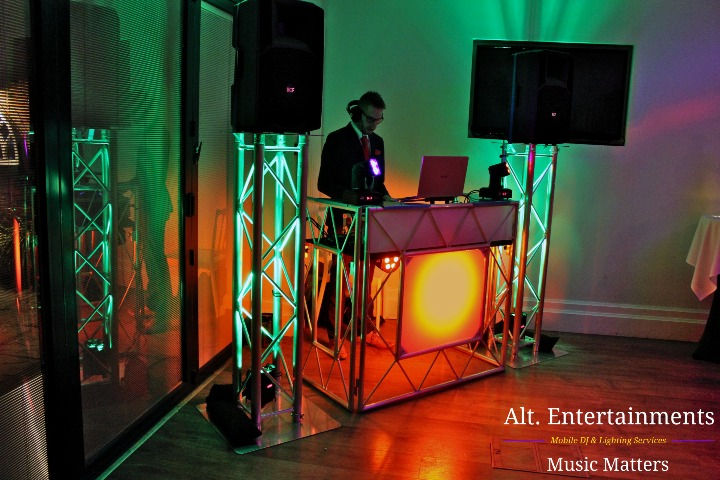Alt. Entertainments DJ setup bathed in green and orange light, creating a mesmerizing atmosphere at St. Johns Luxury B&B wedding reception. A dance-ready haven filled with vibrant vibes.
