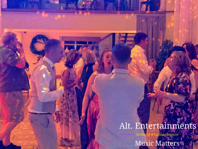 Friends and family dancing together at a wedding reception at The Barns at Delbury Hall near Craven Arms, Shropshire, photographed by Alt. Entertainments.