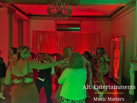 Guests enjoying a lively dance at a wedding disco at Garthmyl Hall, Montgomery, Wales. The photo, taken by Alt. Entertainments, shows people dancing energetically on a well-lit dance floor surrounded by colorful lighting and elegant decorations, reflecting the vibrant and festive atmosphere created by their Mobile DJ, Wedding DJ, Indie DJ, and Alternative DJ services.