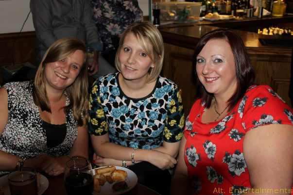 Group of people happily posing for a photo during an event at Tettenhall Albert Lawn Tennis Club in Wolverhampton. The image, taken by Alt. Entertainments, showcases smiling attendees against the club’s scenic backdrop of lush greenery and charming architecture. The professional DJ setup in the background hints at the lively entertainment provided, contributing to the joyful atmosphere of the event.