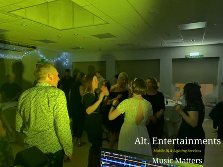 Wedding guests dancing energetically at Wolverhampton Lawn Tennis & Squash Club in Tettenhall. The lively photo shows a packed dancefloor illuminated by vibrant lighting, with music and entertainment provided by Alt. Entertainments Wedding DJ/Mobile DJ, Disco & Events Company.