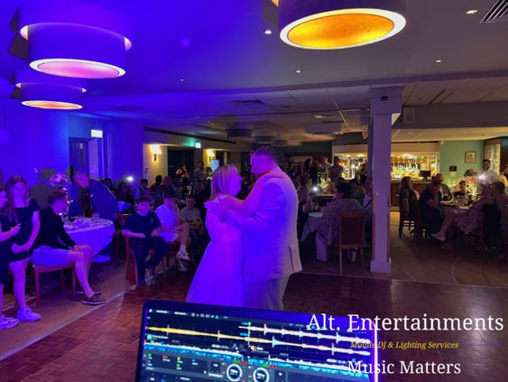 Bride and groom sharing their first dance under soft uplighting and fairy lights at Copt Heath Golf Club in Knowle, surrounded by smiling guests; music and lighting by Alt. Entertainments Wedding DJ/Mobile DJ, Disco & Events Company.