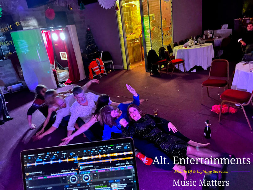 A lively disco night at Scholes Mill in Matlock, Derbyshire, organized by Alt. Entertainments, a Mobile DJ, Disco & Events Company. The photo captures people dancing enthusiastically under colorful lights, enjoying the vibrant atmosphere created by professional sound and lighting equipment. The historic venue adds a unique charm to the festive scene.