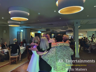 Photo of a bride and groom sharing their first dance beneath fairy lights and soft uplighting at Copt Heath Golf Club in Knowle, surrounded by applauding guests; music and lighting by Alt. Entertainments Wedding DJ/Mobile DJ, Disco & Events Company.
