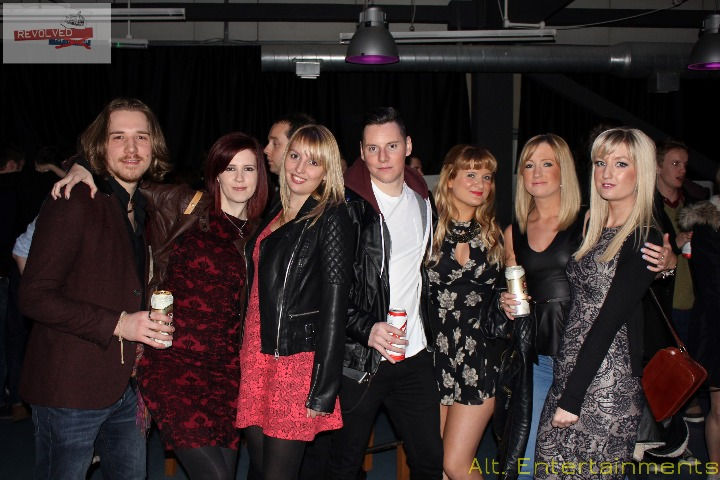 A group of people posing for a photo at the Revolved Indie Night Reunion held at Fixxion Warehouse in Wolverhampton. The photo, taken by Alt. Entertainments, shows attendees in indie-inspired outfits enjoying the event, with the modern and spacious Fixxion Warehouse serving as the backdrop. The event, previously hosted at the Light Bar, reflects a transition to a new venue that accommodates a larger crowd and enhances the celebration experience.