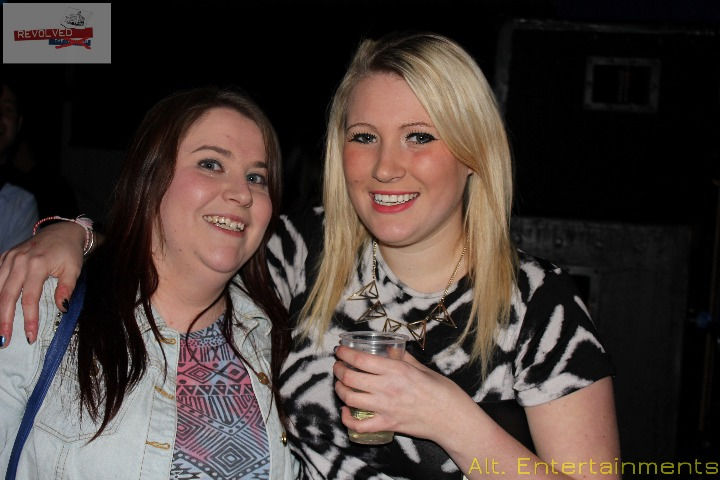 Group of people posing for a photo at the Revolved Indie Night Reunion, held at Fixxion Warehouse in Wolverhampton. The event, previously held at the Light Bar, is captured in this photo taken by Alt. Entertainments, a mobile DJ and events company. The attendees, dressed in indie fashion, are smiling and celebrating in the lively and modern setting of Fixxion Warehouse, capturing the festive and inclusive atmosphere of the reunion.