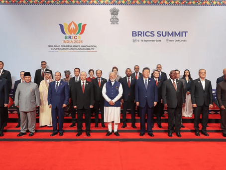 Group of world leaders pose on a red-carpeted stage at BRICS Summit, with BRICS India 2026 and BRICS SUMMIT signs.