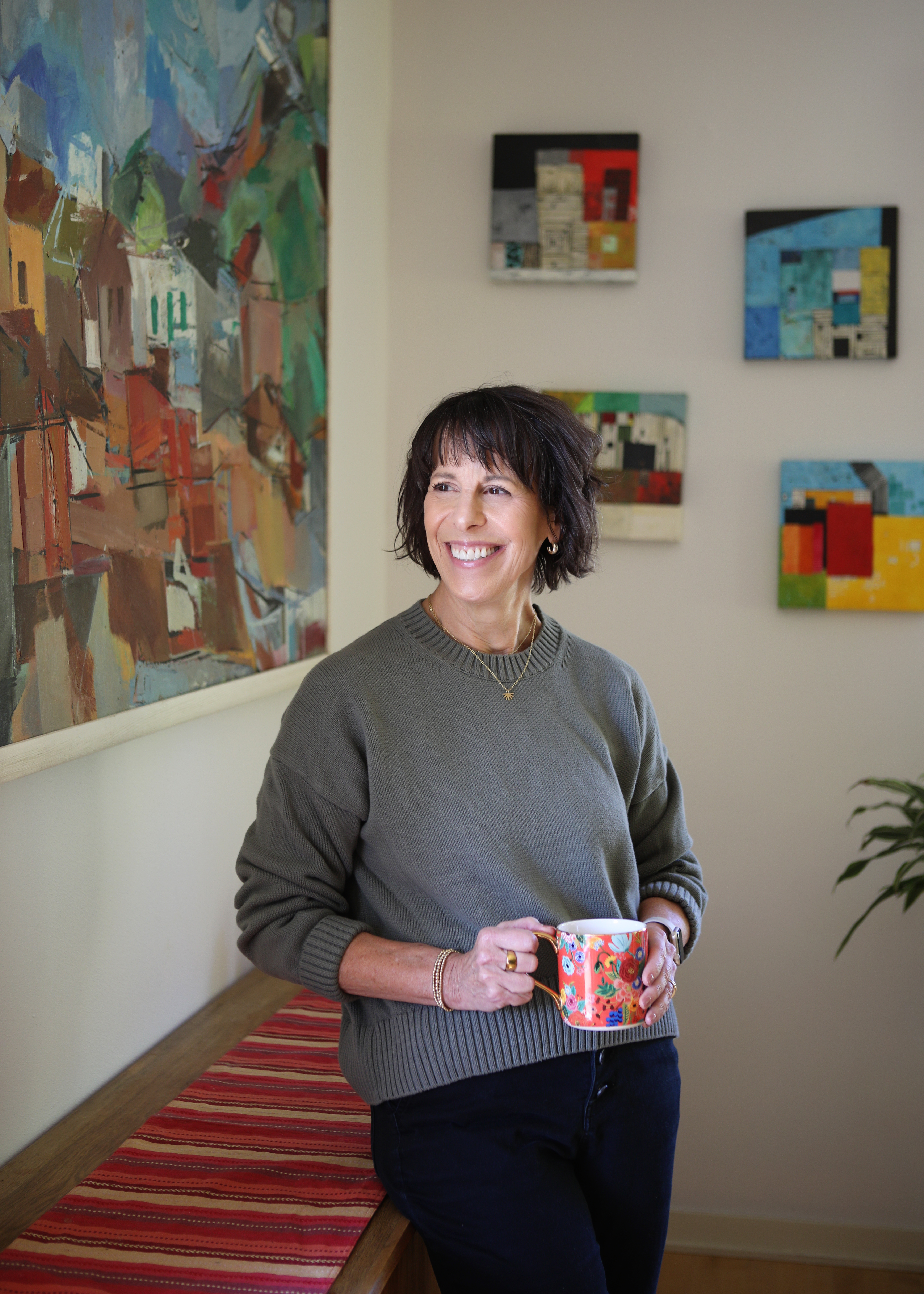 portrait of jane leaning on wall holding coffee mug