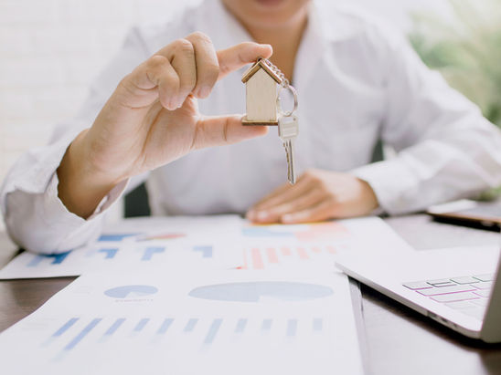 A person in white suit holding up a house key.