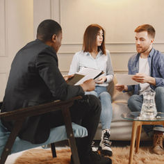 A couple in a couch, talking with a male agent.