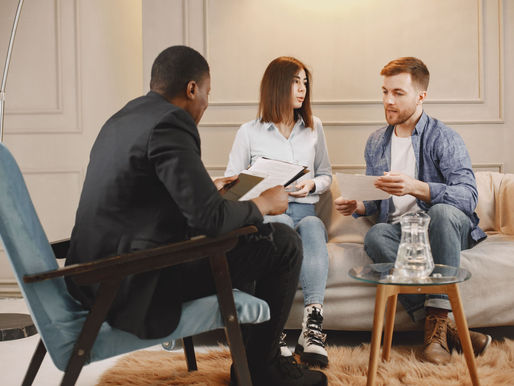 A couple in a couch, talking with a male agent.