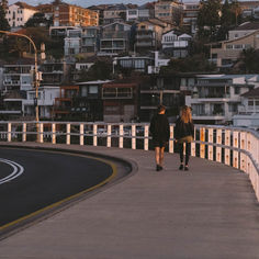 A couple walking along street of Sydney, with houses a far.