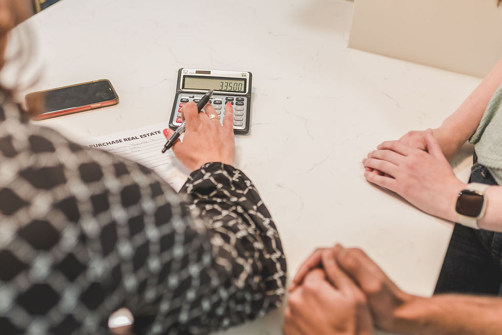 Several people gathered on a table, while a person's hand using a calculator.