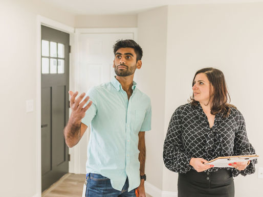 A female agent with a male client talking inside an empty house.