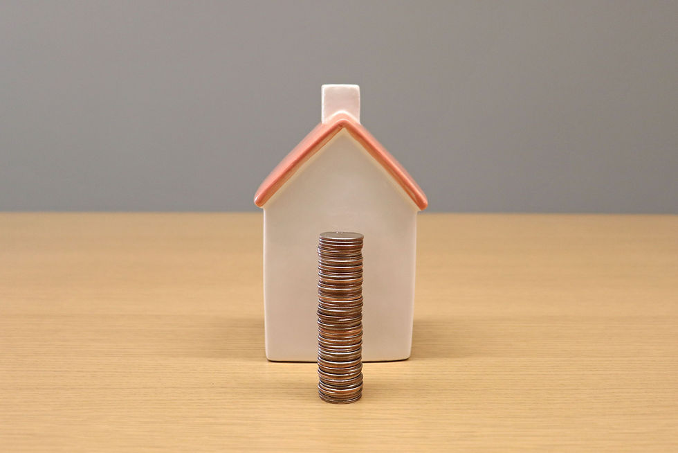 A miniature house with stacked coins placed in front of it.
