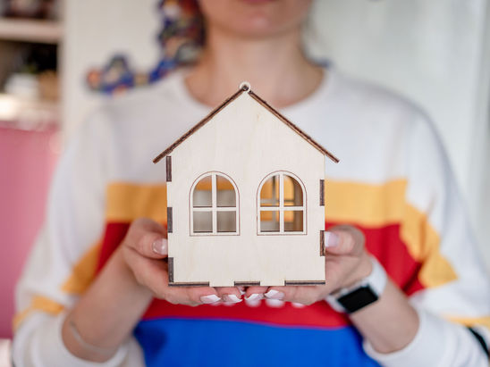 A person holding up a miniature house model.
