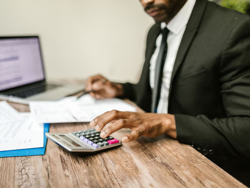 A male in suit computing using a calculator.