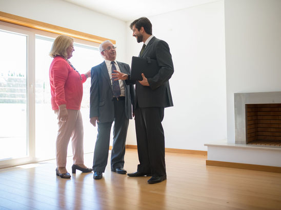 A retired couple engaged in conversation with a male agent.