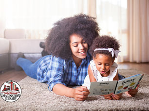 A mother and daughter laying on the floor reading a book called Sassy. The Dolly Parton’s Imagination Library logo can be seen in the bottom.