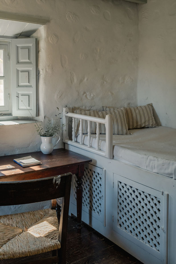 Minimal Mediterranean-style room with built-in daybed, wooden table, and soft natural light