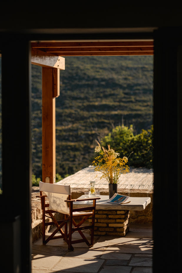 Outdoor terrace with wooden chair and stone table overlooking mountains at a traditional luxury retreat.