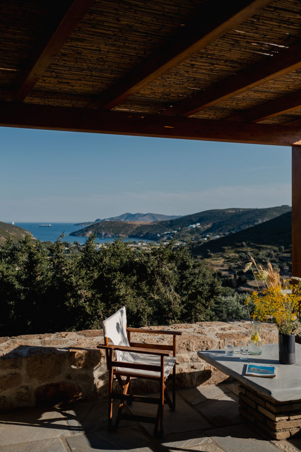 Outdoor terrace with sea and mountain views under a wooden pergola at a countryside guesthouse.