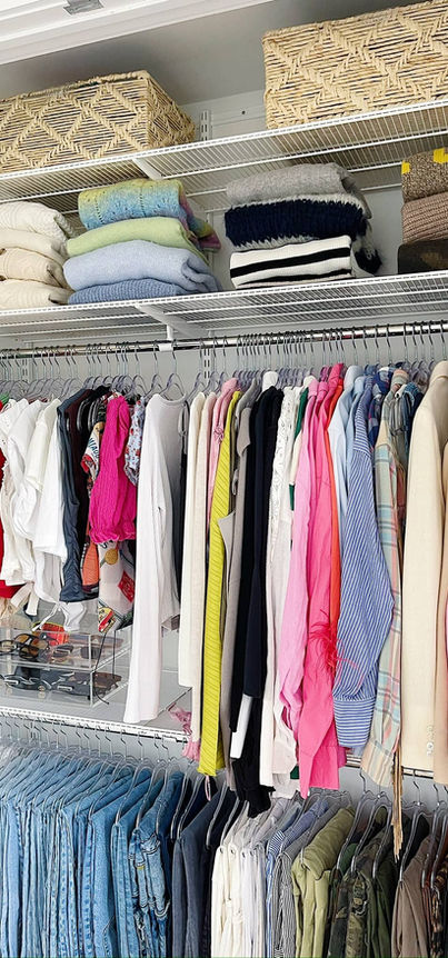 Organized closet with colorful clothes hung on racks and folded on shelves.