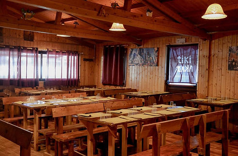 Sala interna della pizzeria Tiki Taka con tavoli in legno.
