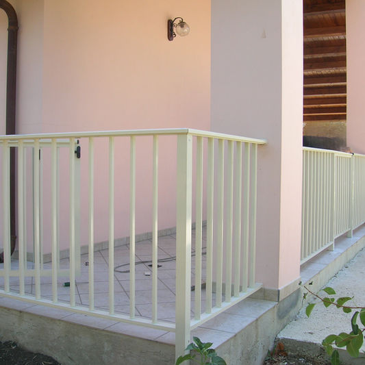 Ringhiera in alluminio bianco su un porticato esterno.
