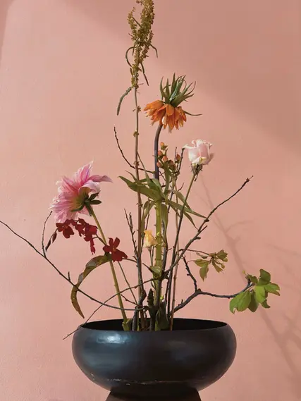 Composizione floreale ikebana in vaso scuro