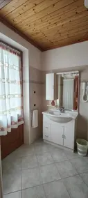 Bagno con lavabo bianco e soffitto in legno.