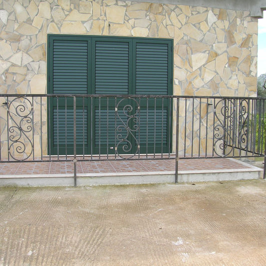 Ringhiera in metallo decorata davanti a un infisso verde